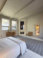 Bedroom with lofted ceiling with beams, a large fireplace, and wooden ceiling