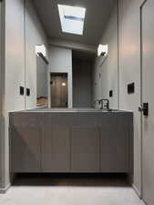 Bathroom featuring double vanity, a skylight, and baseboards