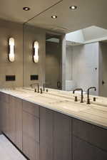 Full bath with double vanity, a sink, tile walls, and recessed lighting