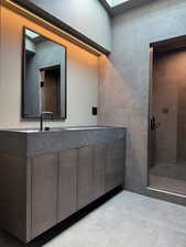 Bathroom featuring a stall shower, tile walls, and vanity