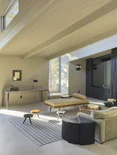 Living room featuring beam ceiling and concrete floors