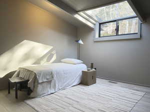 Bedroom featuring visible vents, vaulted ceiling with beams, baseboards, and wood finished floors