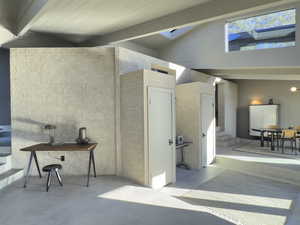 Home office with finished concrete floors, a skylight, beamed ceiling, and high vaulted ceiling