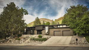 View of front of house featuring a garage, concrete driveway, a chimney, a mountain view, and stucco siding