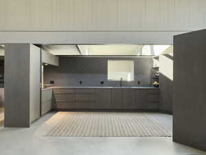 Kitchen featuring tasteful backsplash, modern cabinets, a sink, and finished concrete floors