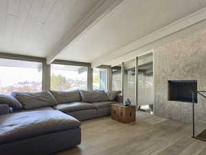 Living area featuring beam ceiling, a fireplace, and hardwood / wood-style floors