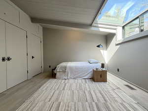 Unfurnished bedroom with beamed ceiling, wood finished floors, and visible vents