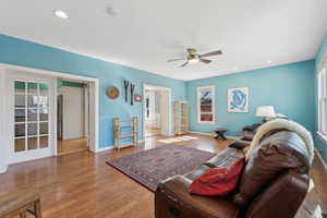 Living area featuring baseboards, wood finished floors, a ceiling fan, and recessed lighting