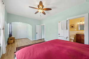 Bedroom with arched walkways, ensuite bathroom, a ceiling fan, a sink, and wood finished floors