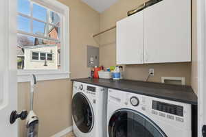 Laundry area with electric panel, cabinet space, and washer and dryer