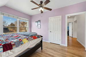 Bedroom featuring vaulted ceiling, ceiling fan, light wood finished floors, and baseboards