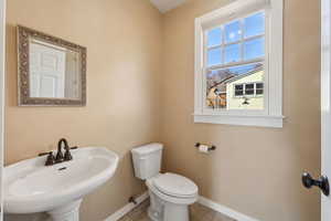 Half bath featuring toilet, baseboards, and a sink