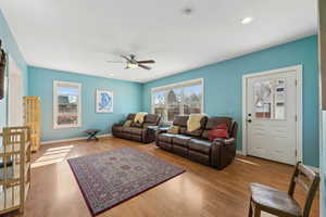 Living room featuring baseboards, recessed lighting, wood finished floors, and a healthy amount of sunlight