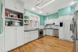 Kitchen featuring dark countertops, tasteful backsplash, stainless steel appliances, and a sink