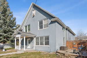 View of front of house featuring covered porch, fence, and stucco siding