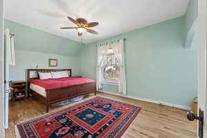 Bedroom with ceiling fan, vaulted ceiling, baseboards, and wood finished floors