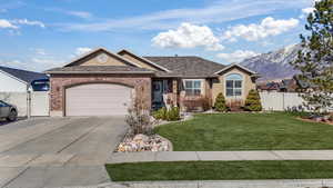 Ranch-style house with a garage, concrete driveway, a gate, fence, and a front lawn