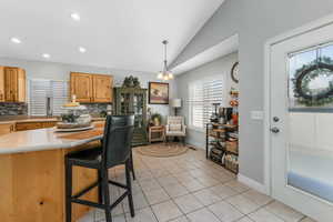 Kitchen with lofted ceiling, light tile patterned flooring, a sink, light countertops, and backsplash