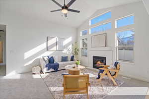 Living room with visible vents, a ceiling fan, carpet floors, a fireplace, and high vaulted ceiling