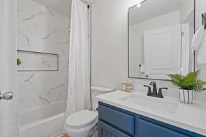 Full bathroom with shower / bath combo with shower curtain, vanity, and toilet