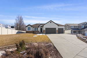 View of front facade featuring brick siding, concrete driveway, an attached garage, a front yard, and fence