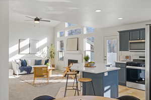 Kitchen with a breakfast bar, stainless steel appliances, light countertops, open floor plan, and a kitchen island