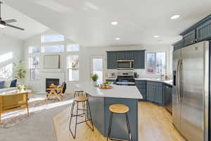 Kitchen featuring a sink, open floor plan, light countertops, appliances with stainless steel finishes, and a kitchen bar