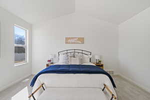 Carpeted bedroom with lofted ceiling, visible vents, and baseboards