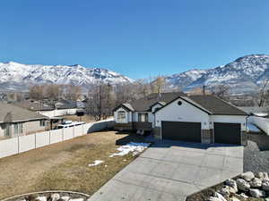 View of front facade featuring fence private yard, a mountain view, a garage, brick siding, and driveway