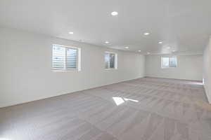 Basement with baseboards, recessed lighting, and light colored carpet