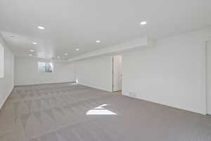 Below grade area with baseboards, recessed lighting, visible vents, and light colored carpet