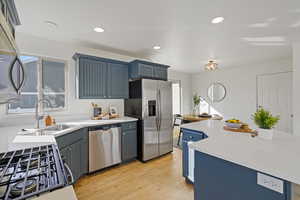 Kitchen featuring light wood-style flooring, recessed lighting, stainless steel appliances, a sink, and blue cabinetry