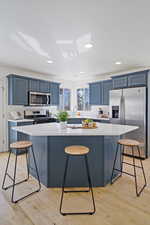 Kitchen featuring blue cabinets, light wood-type flooring, stainless steel appliances, and light countertops