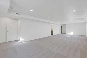 Interior space with recessed lighting, light colored carpet, visible vents, and baseboards