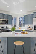 Kitchen featuring a sink, appliances with stainless steel finishes, a kitchen breakfast bar, and light countertops