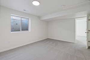 Carpeted empty room featuring visible vents and baseboards