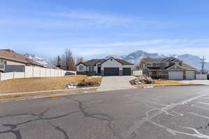 View of front of house with a garage, driveway, fence, and a mountain view