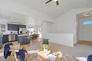 Living room with light wood finished floors, baseboards, ceiling fan, vaulted ceiling, and recessed lighting