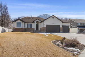 View of front of home with a garage, concrete driveway, fence, a mountain view, and brick siding