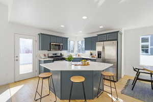 Kitchen featuring appliances with stainless steel finishes, a breakfast bar, light countertops, and a center island