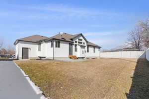 View of front facade featuring entry steps, a shingled roof, a fenced backyard, a front yard, and stucco siding