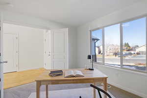 Office area with visible vents, light wood-style flooring, and baseboards