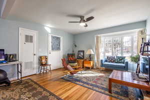 Living room with visible vents, ceiling fan, baseboards, and wood finished floors