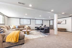 Carpeted living area featuring a textured ceiling, visible vents, and recessed lighting