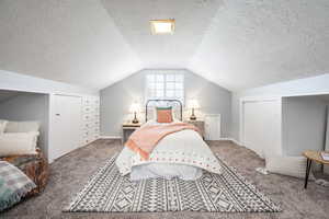 Bedroom with carpet floors, lofted ceiling, a closet, a textured ceiling, and baseboards