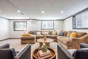 Living area featuring light carpet, visible vents, ornamental molding, and a textured ceiling