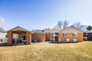 Back of property featuring brick siding, a yard, a patio, a mountain view, and fence