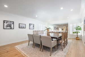 Dining room with baseboards, light wood-style floors, and crown molding