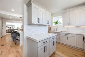 Kitchen featuring recessed lighting, light wood-type flooring, light stone countertops, and decorative backsplash