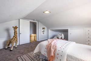 Bedroom featuring a textured ceiling, baseboards, vaulted ceiling, and carpet flooring